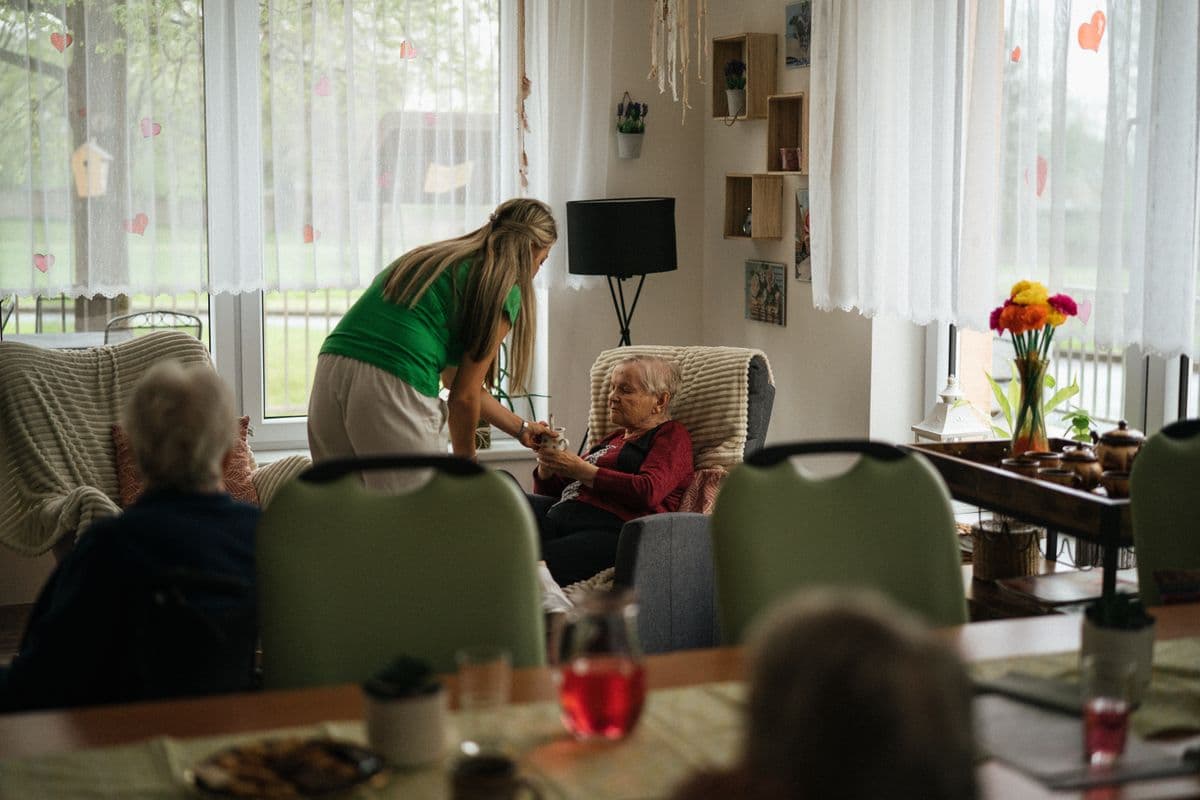 A caregiver assists a resident in her armchair