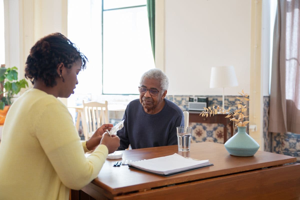 A caregiver reviews medication with a resident at the table